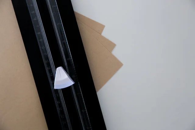 Close-up of a paper trimmer on a table cutting brown sheets with precision. Bookbinding mistakes: what a beginner's notebook should record