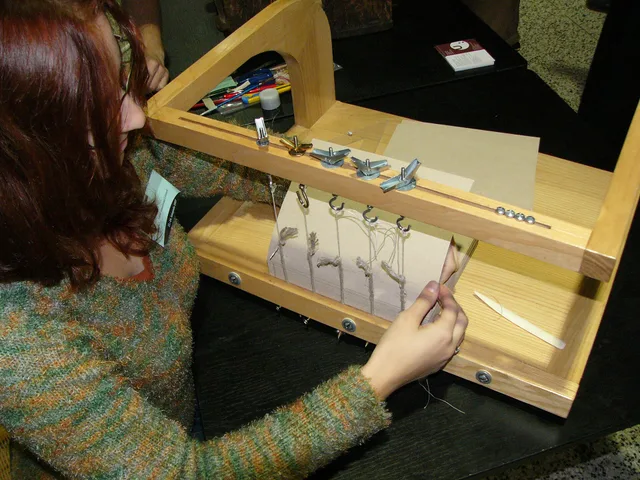 bookbinding on sewing frame. There is bone folder (folding stick) on the right too. Which bookbinding tools earn their price, and which are a budget trap?