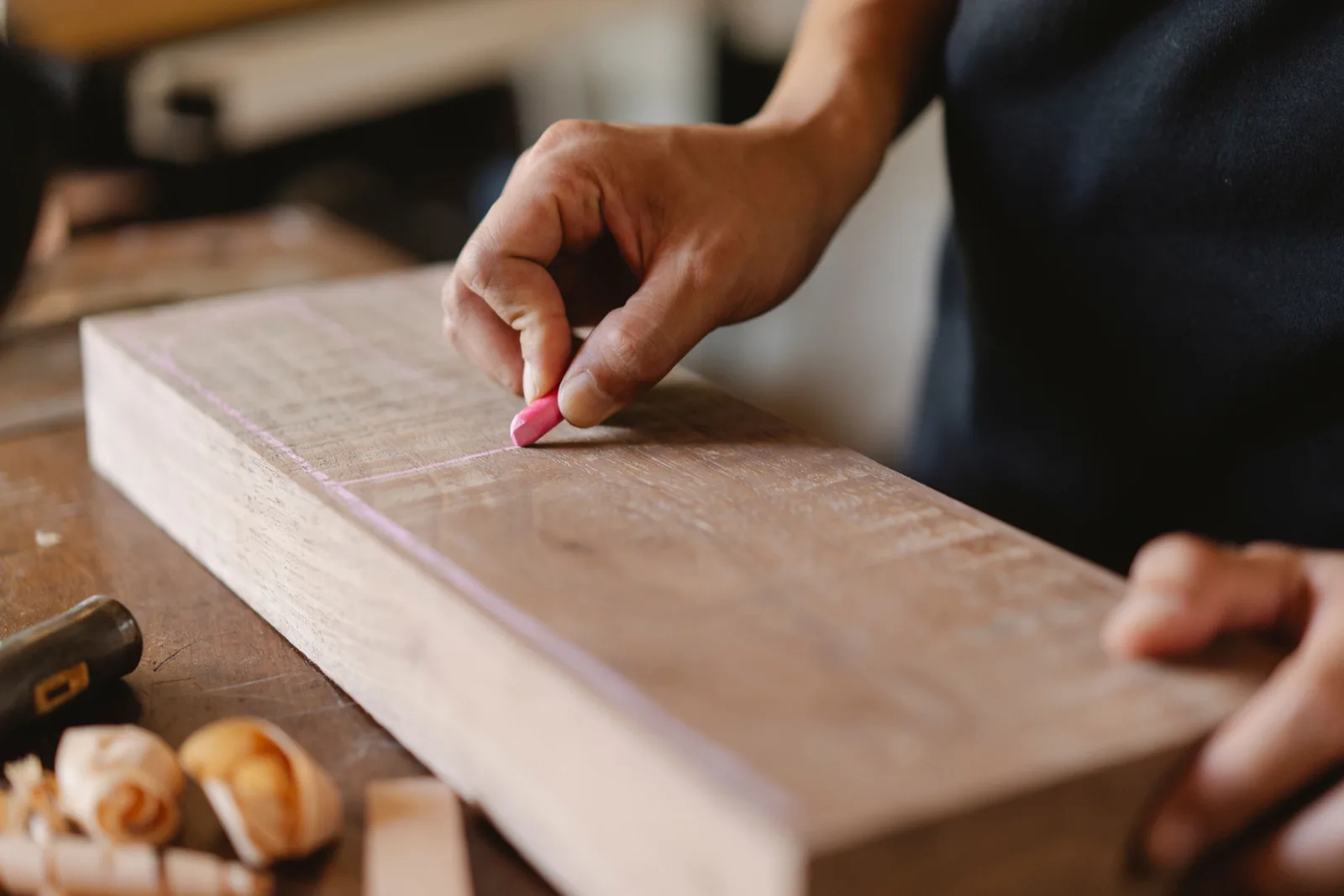 Crop anonymous woodworker drawing vertical line on rectangular wooden piece using colored chalk in workshop. 5 things worth knowing about book arts mistakes
