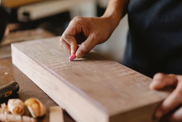 Crop anonymous woodworker drawing vertical line on rectangular wooden piece using colored chalk in workshop. 5 things worth knowing about book arts mistakes