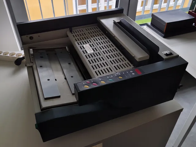 Bench-top hot-melt adhesive binding machine for books and documents (semi-automatic spine gluer) – bookbinding binder. The machine is used for softcover binding (for example, of dissertations, catalogues or reams of paper) using hot-melt adhesive. The machine is located in the bookbinders’ workshop. Choosing recoverable materials keeps a bookbinding mistake from becoming permanent