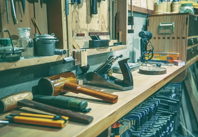 A tidy workshop bench with various woodworking tools and clamps neatly arranged. Archival standards for handmade books at the bench