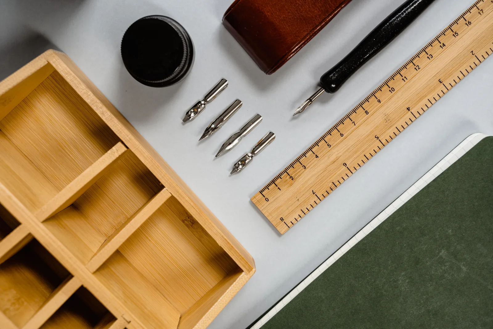 Flat lay of vintage stationery including ink, pen nibs, and a wooden ruler on a desk. When does storage matter more to book arts than technique itself?